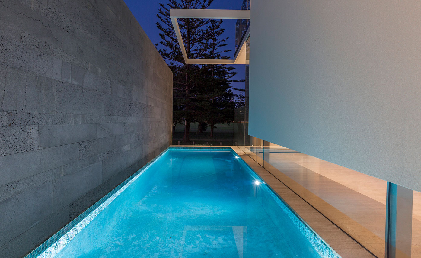 Grey Stone Accent Wall Adjacent Pool of Exterior Entryway of Home